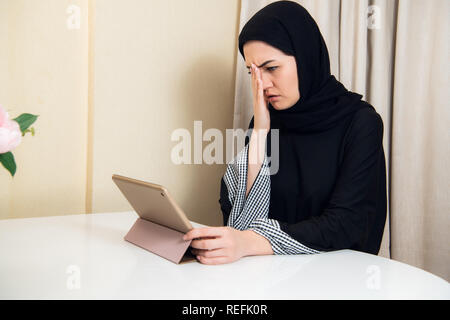 Triste d'affaires musulmanes woman holding a tablet à la maison ou au bureau Banque D'Images