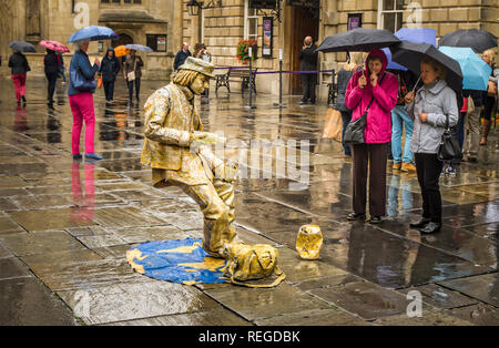 Artiste de rue attirer la curiosité de la foule lors d'une journée pluvieuse à Bath au Royaume-Uni Banque D'Images