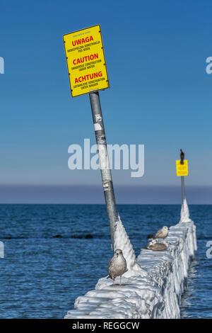 Épis couvertes de glace à la plage de la mer Baltique près de Kolobrzeg. Sur les épis il y a des signes dans les langues Polonais, Anglais et Allemand Banque D'Images