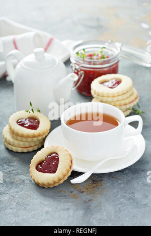 Linzer cookies avec de la confiture et de remplissage forme coeurs servi avec du thé Banque D'Images