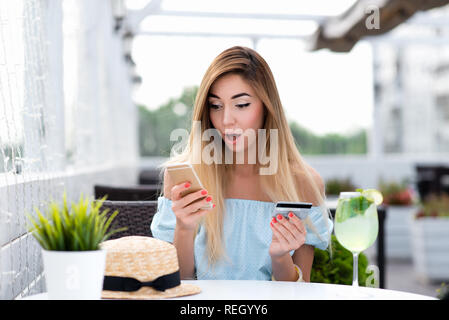 Café de fille en été. Payer le petit déjeuner et le déjeuner avec carte de plastique par téléphone via l'application Internet. L'émotion de surprise, choquée produit de valeur. Concept de malentendu confusion grande radiation. Banque D'Images