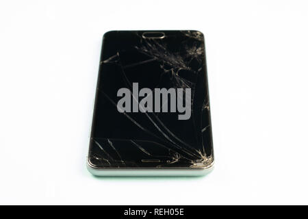 Téléphone mobile avec écran noir cassé, vue du dessus. Smartphone endommagé en détresse dans l'arrière-plan vert pâle, faible profondeur de champ Banque D'Images