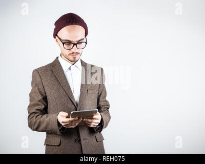 Veste en tweed homme sérieux avec un ordinateur tablette. Personne de sexe masculin dans les vêtements de style hippie utilise la technologie, studio shot in white background Banque D'Images