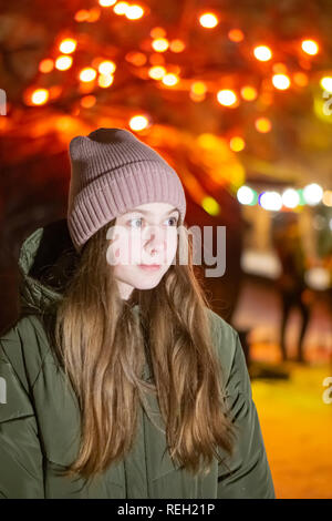 Belle fille à la recherche vers le bas sur la rue de la ville de nuit sur la toile de fond avec devanture rougeoyant. bokeh. L'espace de copie de l'inscription ou d'objets Banque D'Images