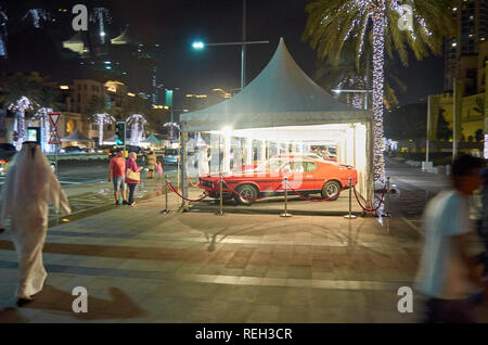 La vie nocturne dans la ville de Dubaï. Les hommes arabes portant des kandoras pied de luxe, des voitures garées et arbres illuminés décorer l'étonnant centre ville de Dubaï, Unite Banque D'Images