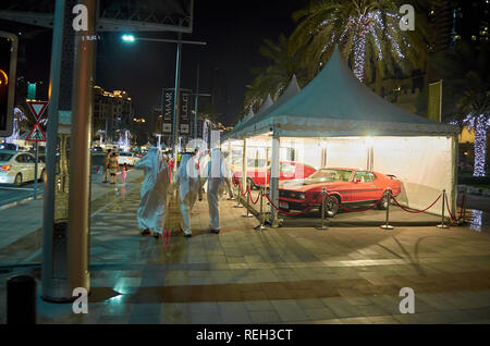 La vie nocturne dans la ville de Dubaï. Les hommes arabes portant des kandoras pied de luxe, des voitures garées et arbres illuminés décorer l'étonnant centre ville de Dubaï, Unite Banque D'Images