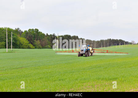 Machine agricole féconde un champ vert au printemps Banque D'Images