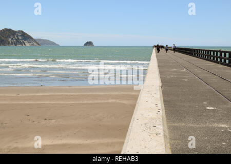 Les gens à pied le long du quai sous le soleil d'inTolaga Bay, Nouvelle-Zélande Banque D'Images