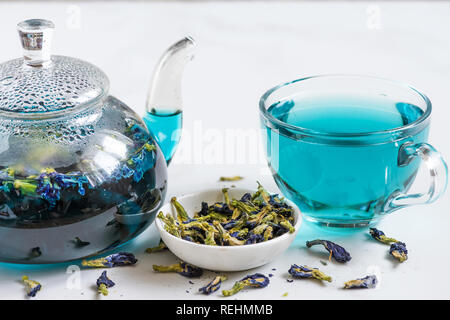 Tasse de thé pois papillon bleu ou un thé avec théière transparente pour une boisson detox sur table de marbre blanc. close up Banque D'Images