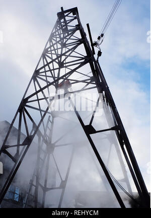 Une structure de tour en acier métal avec des câbles attachés à elle. La vapeur blanche sont issues de la base de la tour. Banque D'Images