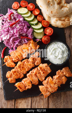 Taouk traditionnelle brochette de poulet avec une salade fraîche, sauce yogourt et de pain pita close-up sur la table. Haut Vertical Vue de dessus Banque D'Images