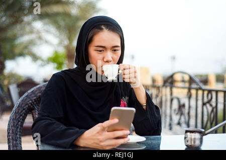 Femme musulmane ayant une tasse de café dans un bar Banque D'Images