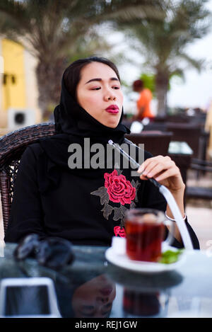 Femme musulmane fumeurs de narguilé dans un café-bar Banque D'Images