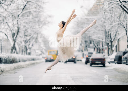 Belle jupe transparente en ballerine danse et de sauter sur la rue de snowy city parmi les voitures. Banque D'Images