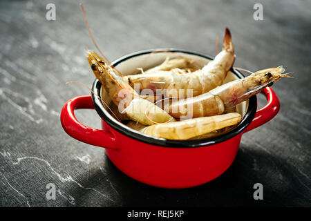 Délicieux crus frais crevettes géantes dans un pot rouge sur une table en bois noir Banque D'Images