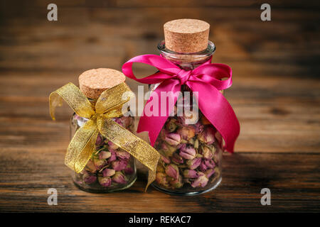 Bourgeons rose dans un pot en verre sur fond de bois Banque D'Images