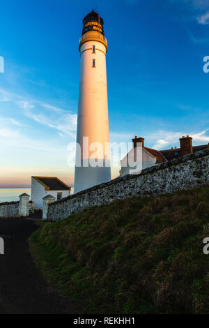 Scurdie Ness phare au crépuscule. Le phare protège l'expédition à partir de l'éperon rocheux de la côte écossaise. Banque D'Images