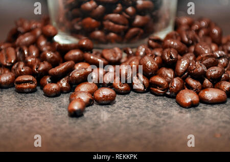 Grains de café en verre entouré de grains de café. Banque D'Images