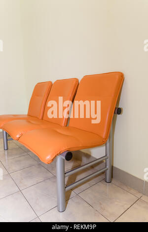 Bâtiment public d'attente. Détail de l'intérieur de l'hôpital. Personne n.hall de l'hôpital pour les patients en attente chaises orange pour le médecin visite.espace d'attente intérieur.sièges vides. Banque D'Images