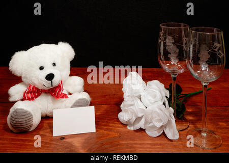 Beaux verres à vin gravés avec des roses blanches et l'ours blanc et l'étiquette-nom sur la table en bois et un arrière-plan sombre. La Saint-Valentin, fête des Mères, Pâques, Banque D'Images