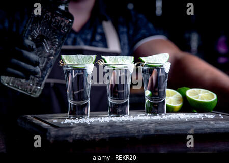 Apéritif entre amis dans le bar, trois verres d'alcool avec de la chaux et du sel pour la décoration. Tequila shots, selective focus Banque D'Images