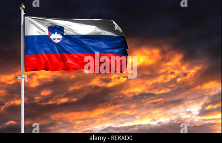 Drapeau de la Slovénie le mât voletant dans le vent contre un ciel coucher de soleil coloré. Banque D'Images