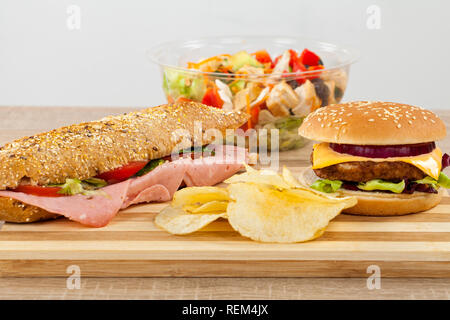 Ciabatta frais sandwich avec jambon de porc et légumes, délicieux cheeseburger et croustilles de pommes de terre sur une planche à découper en bois Banque D'Images