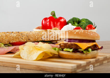 Ciabatta frais sandwich avec jambon de porc et légumes, délicieux cheeseburger et croustilles de pommes de terre sur une planche à découper en bois Banque D'Images