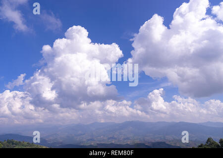 Dramatique nuages duveteux blanc sur bleu ciel au-dessus de la montagne verte Banque D'Images