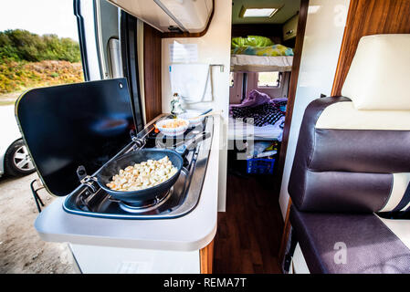 Cuire le dîner ou déjeuner dans un camping-car, camping-car ou camping. La préparation de poulet dans une casserole dans le camping-car lorsque vous voyagez avec RV, autocaravane caravane ou motorva Banque D'Images