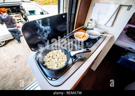 Cuire le dîner ou déjeuner dans un camping-car, camping-car ou camping. La préparation de poulet dans une casserole dans le camping-car lorsque vous voyagez avec RV, autocaravane caravane ou motorva Banque D'Images