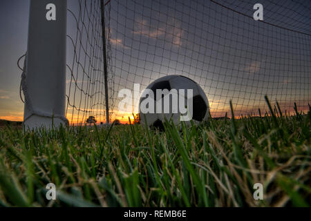 Vue au niveau du sol d'un ballon de foot dans un but Banque D'Images
