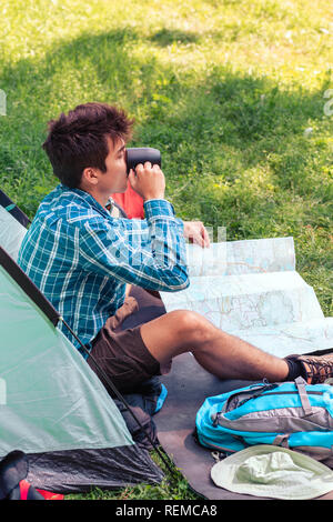 Passer un séjour sur le camping. Jeune homme prochain voyage de planification et de boire un café Banque D'Images