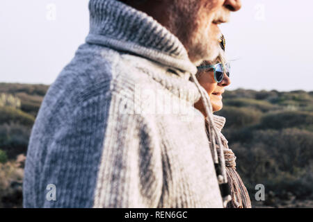 Portrait fashion style vieux couple de seniors homme et femme avec la nature en arrière-plan - la saison froide de l'automne ou au printemps et soleil Banque D'Images