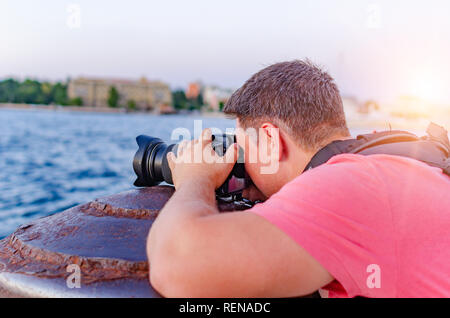 Homme avec un appareil photo photographier le coucher du soleil sur la côte. Banque D'Images