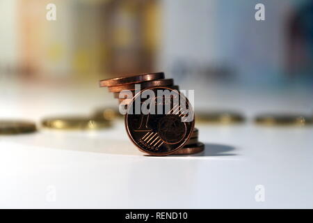 Un cent euro coin placé avec douze pièces sur une table avec des billets en euros derrière Banque D'Images