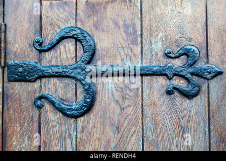 Un hôtel de style Tudor de charnière de porte en fonte. La charnière est sur une porte en bois. Banque D'Images