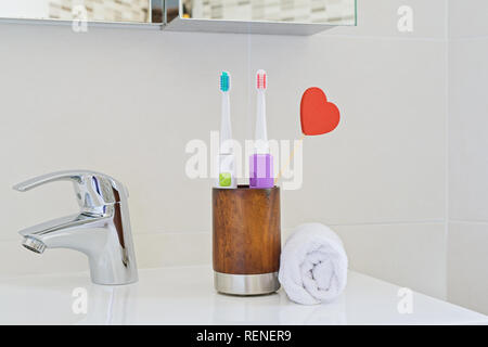 Deux brosses à dents en bois verre sur l'évier dans la salle de bains avec cœur rouge. Brosse à dents Soins personnels Soins dentaires. Hygiène dentaire oral. Den Banque D'Images