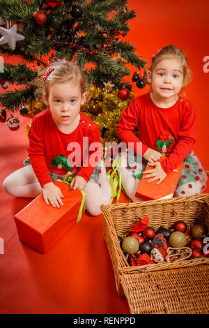 Deux petites filles déballer leurs cadeaux dans les boîtes rouges Banque D'Images