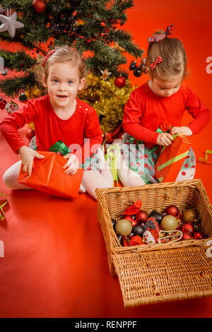 Deux petites filles déballer leurs cadeaux dans les boîtes rouges Banque D'Images