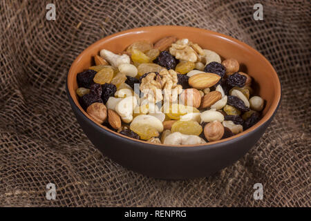 Un mélange de fruits secs dans une cuvette ronde sur de la toile de jute. Vue de côté. Banque D'Images