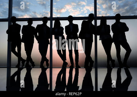 Silhouette d'une équipe entreprises debout à côté de la fenêtre du bureau Banque D'Images