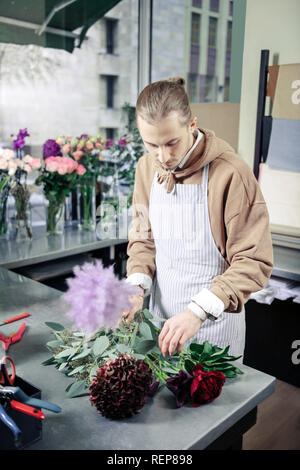 Jeune fleuriste concentré des fleurs pour l'ikebana Banque D'Images