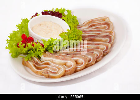 Oreilles de porc fumé avec une sauce à l'ail et la laitue sur fond blanc Banque D'Images