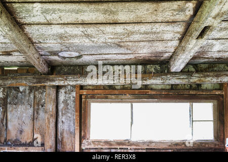 Et a disparu de la fenêtre en bois peint blanc revêtus de plafond avec poutres apparentes et murs tronc de l'arbre à l'intérieur d'un old weathered barn Banque D'Images