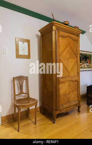 Fauteuil en bois ancien et grand French style armoire bois dans la chambre principale à l'étage dans une ancienne maison de style en pierre des Canadiana 1839 Banque D'Images