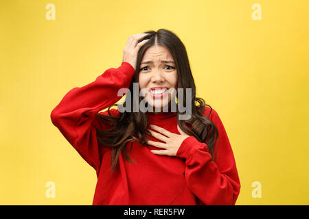 Choqué peur belle jeune femme avec la bouche largement ouverte, la caméra regarde se rend compte qu'elle a déçu avec quelque chose, isolé sur fond jaune studio. Banque D'Images