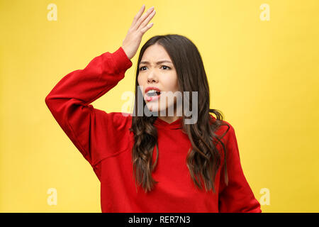 Choqué peur belle jeune femme avec la bouche largement ouverte, la caméra regarde se rend compte qu'elle a déçu avec quelque chose, isolé sur fond jaune studio. Banque D'Images