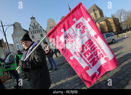 Rostock, Allemagne. 23 Jan, 2019. Au cours d'un rassemblement à l'intérieur de la journée de grève d'avertissement dans la fonction publique, un homme porte un drapeau avec l'inscription '6 pour cent doit être'. Le Verdi et dbb syndicats exigent six pour cent plus payer, mais au moins 200 euros par mois. Crédit : Bernd Wüstneck/dpa/ZB/dpa/Alamy Live News Banque D'Images