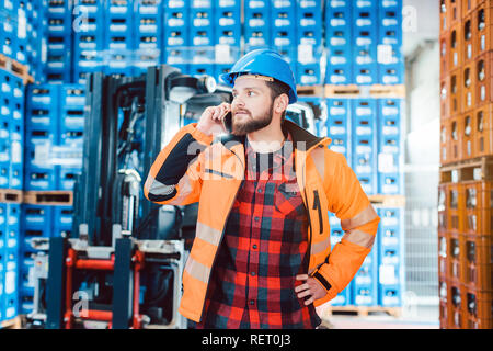 Travailleur dans l'entrepôt logistique sur le téléphone Banque D'Images